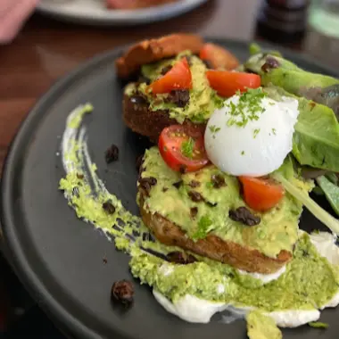 Smashed avocado on toast with a poached egg and cherry tomatoes