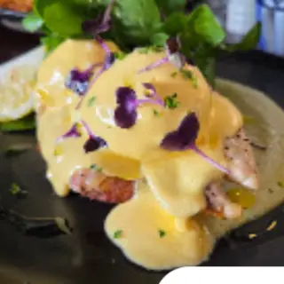 Eggs benedict under hollandaise, scattered with purple flowers