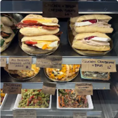 Shelves of filled rolls and salads in the cabinet, with handwritten labels