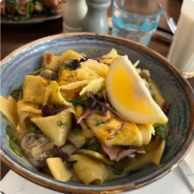 Ribbons of pasta with mushrooms and a lemon wedge