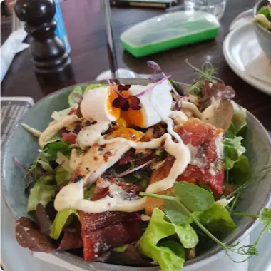 A leafy salad topped with a soft egg and a creamy dressing